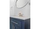 Close-up of a blue bathroom vanity featuring a modern faucet and round mirror at 2943 Willowleaf Ln, Wesley Chapel, FL 33544