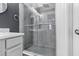 This modern shower features gray tile, glass doors, and a stylish herringbone floor at 2943 Willowleaf Ln, Wesley Chapel, FL 33544