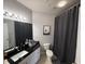 Bright bathroom with a black granite countertop, gray shower curtain and tile flooring at 4333 Bayside Village Dr # 310, Tampa, FL 33615