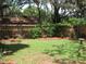 Large backyard features a well-kept lawn, flowering bushes, and a wooden privacy fence at 7026 Lenape Cir, New Port Richey, FL 34653