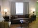 Comfortable living room with a tufted brown sofa, accent tables, and bright natural light at 7026 Lenape Cir, New Port Richey, FL 34653