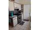 Compact kitchen featuring stainless steel appliances, decorative tile backsplash, and white cabinetry at 7418 Riverbank Dr, New Port Richey, FL 34655
