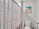 A bright bathroom featuring a tub, shower curtain, and artwork at 5289 Fiddle Fig Ave, Wimauma, FL 33598