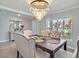Elegant dining room with a stunning chandelier, modern furnishings, and natural light streaming through the window at 5289 Fiddle Fig Ave, Wimauma, FL 33598