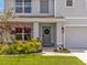 A welcoming front entrance with landscaped garden, stone accents, and a wreath on the gray front door at 5289 Fiddle Fig Ave, Wimauma, FL 33598