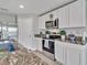 This kitchen features stainless steel appliances and granite countertops with white cabinets at 5289 Fiddle Fig Ave, Wimauma, FL 33598