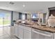 Kitchen island with sink overlooks the living room with backyard access through sliding glass door at 5289 Fiddle Fig Ave, Wimauma, FL 33598