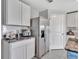 Well-equipped kitchen with stainless steel refrigerator, white cabinetry, granite counters, and modern tile backsplash at 5289 Fiddle Fig Ave, Wimauma, FL 33598
