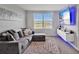 Modern living room with a comfortable gray sectional sofa, sleek entertainment center, and large window views at 5289 Fiddle Fig Ave, Wimauma, FL 33598