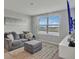 Comfortable living room featuring a gray sofa, ottoman, large window, and mounted TV at 5289 Fiddle Fig Ave, Wimauma, FL 33598