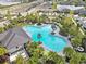An aerial view of a community pool featuring palm trees, green umbrellas and a nearby playground at 5289 Fiddle Fig Ave, Wimauma, FL 33598