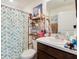 Cozy bathroom featuring a shower with a leafy curtain, a vanity with a white sink, and a storage shelf at 1324 Ocean Spray Dr, Ruskin, FL 33570