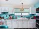 Retro kitchen with white cabinets, vibrant turquoise backsplash, and checkerboard flooring exudes vintage charm at 1790 Pomelo Dr, Venice, FL 34293