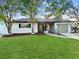 Well-maintained home featuring a stone facade, screened entrance, and a lush green lawn at 7490 Locust Ne St, St Petersburg, FL 33702