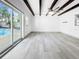 Bright living room with high ceilings, wood beams, a ceiling fan, and a view of the pool through a sliding glass door at 7490 Locust Ne St, St Petersburg, FL 33702