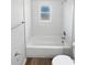 Bathroom features a white tiled tub/shower combo and wood-look flooring at 38832 Henry Dr, Zephyrhills, FL 33542