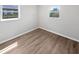 Bright bedroom features wood-look flooring, neutral paint, and natural light from two windows at 38832 Henry Dr, Zephyrhills, FL 33542