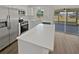 Modern kitchen with stainless steel appliances, white cabinets, peninsula counter, and sliding doors to the lanai at 38832 Henry Dr, Zephyrhills, FL 33542