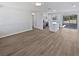 Bright open floor plan featuring a kitchen with white cabinetry and stainless appliances, with modern wood-look flooring at 38832 Henry Dr, Zephyrhills, FL 33542