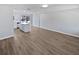 Spacious living room featuring modern wood-look flooring, white walls, and a kitchen area with a white island at 38832 Henry Dr, Zephyrhills, FL 33542