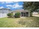View of the backyard with lush green grass, shrubs, and a cozy screened-in porch at 3319 Thistledown Ln, Land O Lakes, FL 34638