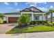 Charming home featuring a manicured lawn, mature landscaping, and a brick-paved driveway leading to a two-car garage at 31840 Magna Gulf Loop, San Antonio, FL 33576