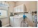 Functional laundry room with a washer, dryer, storage cabinets, and natural light from a window at 31840 Magna Gulf Loop, San Antonio, FL 33576
