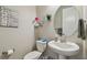 Cozy half-bathroom with a pedestal sink, toilet, and decorative wall art at 31840 Magna Gulf Loop, San Antonio, FL 33576