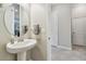 Stylish half-bathroom featuring a pedestal sink, decorative accents, and access to the hallway at 31840 Magna Gulf Loop, San Antonio, FL 33576