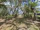 Scenic backyard with mature trees and a glimpse of the water in the distance at 12519 Knollbrook Ln, Hudson, FL 34669