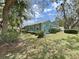 Back exterior view of a blue-green house with white trim and lush landscaping at 12519 Knollbrook Ln, Hudson, FL 34669