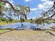 Picturesque pond reflecting blue skies, surrounded by trees and grassy banks at 12519 Knollbrook Ln, Hudson, FL 34669