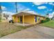 Bright yellow home featuring a covered parking area, blue door, and neatly landscaped yard, blending style and practicality at 2616 Bayshore Gardens Pkwy, Bradenton, FL 34207