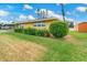 Charming yellow single-story home with a well-manicured lawn, vibrant greenery, and a storage shed at 2616 Bayshore Gardens Pkwy, Bradenton, FL 34207