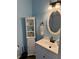 Bathroom with light blue walls, white vanity and cabinet, and beach themed decor at 13122 Cumberland Dr, Largo, FL 33773