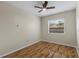 A sunny bedroom with wood floors showcases a window with neighborhood views and a modern ceiling fan at 1904 Crown Park Dr, Valrico, FL 33594