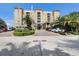 Beautiful tan apartment building featuring lush landscaping, palm trees, and prominent American flags at 1064 N Tamiami Trl # 1219, Sarasota, FL 34236