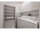 Clean and organized laundry room with white washer, dryer, shelving, and overhead cabinets at 1064 N Tamiami Trl # 1219, Sarasota, FL 34236