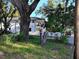 Two-story home with a large tree, landscaping, and a car in the driveway at 820 Bayou Ave, Tarpon Springs, FL 34689