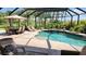 Screened-in pool with an attached spa and patio seating and lush tropical landscaping at 2668 Jablo Cir, North Port, FL 34288