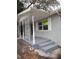 Side view of a gray painted brick home featuring a covered front porch with decorative ironwork and steps at 7240 Donna Dr, New Port Richey, FL 34652