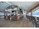 Spacious, covered outdoor bar area with bar seating, televisions, ceiling fans, and a wood plank floor at 5144 Flowing Oar Rd, Wimauma, FL 33598