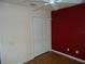 A bedroom with laminate floor, ceiling fan, and red accent wall at 11511 Misty Isle Ln, Riverview, FL 33579