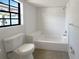 Modern bathroom featuring a tiled shower-tub, a toilet, and a window for natural light at 11114 Shadybrook Dr, Tampa, FL 33625