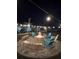 Charming fire pit and chairs on a paved patio, illuminated by string lights, perfect for outdoor entertaining at 27740 Water Ash Dr, Wesley Chapel, FL 33544