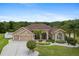 Charming home with manicured lawn, lush landscaping, mature palms, and a three-car garage at 27740 Water Ash Dr, Wesley Chapel, FL 33544