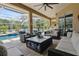 Covered outdoor living space with comfortable seating, a built-in grill, and views of the pool area at 27740 Water Ash Dr, Wesley Chapel, FL 33544
