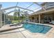Sparkling pool and spa area with screened enclosure, featuring a built-in grill and lounge seating at 27740 Water Ash Dr, Wesley Chapel, FL 33544