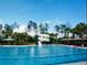 Large community pool with a water slide, lounge chairs, and several cabanas under a blue sky at 27740 Water Ash Dr, Wesley Chapel, FL 33544