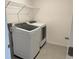 Convenient laundry room featuring modern, white appliances and a wire shelf for ample storage at 32122 Eastern Redbud Br, San Antonio, FL 33576